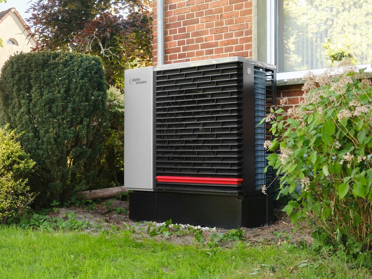 An air-source heat pump beside a brick house